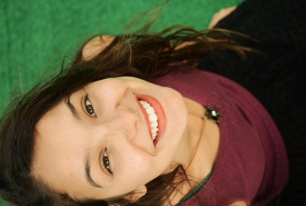 Top-down photo of a young woman looking up at the camera and smiling