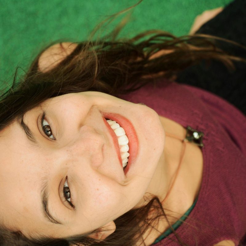 Top-down photo of a young woman looking up at the camera and smiling